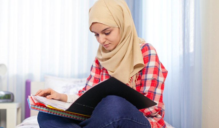 Teenage Muslim girl studying in room