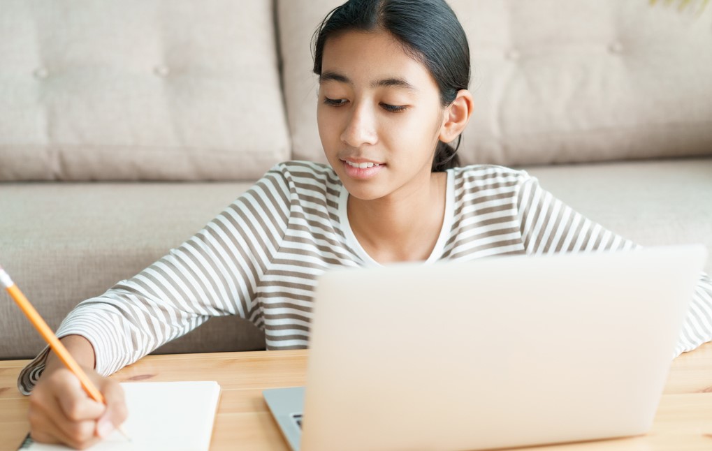Girl studies at laptop at home