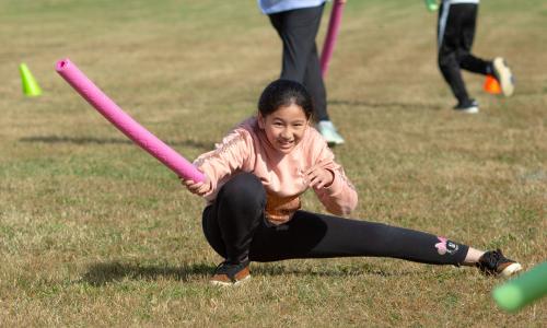 Tips for P.E. Educators: Teaching English Language Learners Girl holding a noodle while lunging in an outdoor PE class