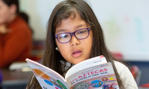 Young girl reading book about Aztecs