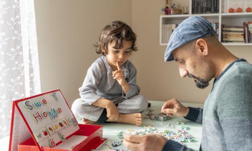 Father and son play with letter magnets
