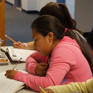 A girl writing in a workbook.