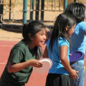 Three laughing children on a playground.