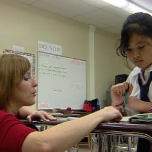 A teacher helping a girl with her school work.