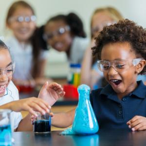 Two children laughing as they do a science experiment with a beaker.