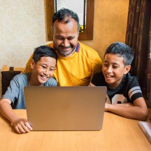Brothers with tablet and laptop at home