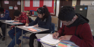 Three young adults writing at their desks