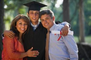 a young man in a cap and gown standing between two adults
