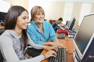 A woman helping a young girl on the computer