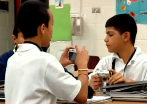 three boys playing with digital cameras