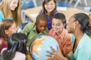 A teacher and students look at a globe