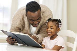 A man helping a young girl read