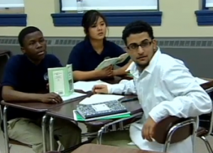 Four students sitting at desks and looking at someone off-camera