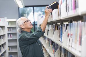man putting book on a bookshelf