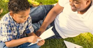 A man and child making paper airplanes