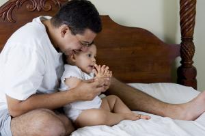 A man sitting in bed with a baby in his lap