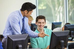 a man showing a young man something on a computer screen