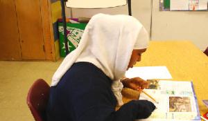 A girl in a hijab reading.