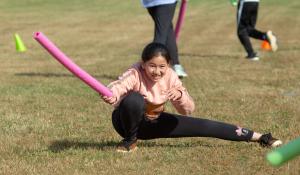 Girl holding a noodle while lunging in an outdoor PE class