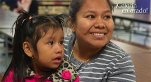 A smiling mom holding her daughter in her lap.