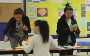 Three teenagers worthing with colored paper at a table.
