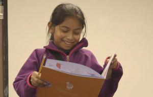 Student reading writing assignment to class