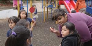Woman talking with kids on a playground.