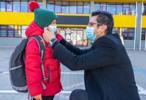 Father adjusting son's face mask