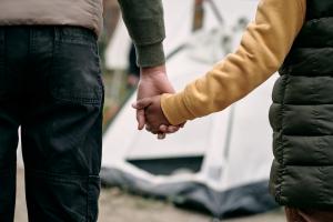 Man holding boy's hand in a migrant camp