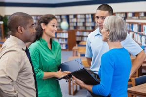 Four adults talking in a library.