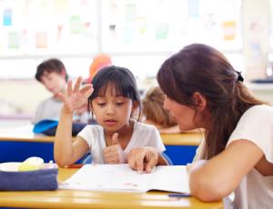 A teacher helping a girl with her school work.
