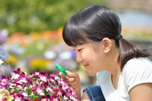 A girl looking at flowers through a magnifying glass.