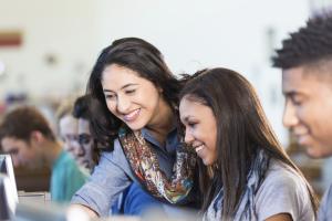 A woman helping a teenader on the computer.
