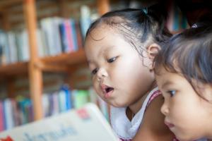 Two very young children looking at a book.