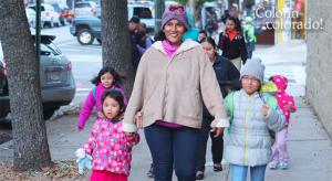 A woman walking two kids to school.