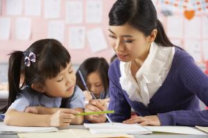 A woman helping a young girl with her schoolwork.