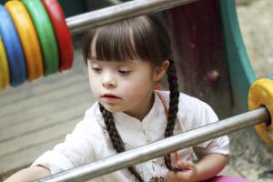 A young girl with Down Syndrome playing on the playground