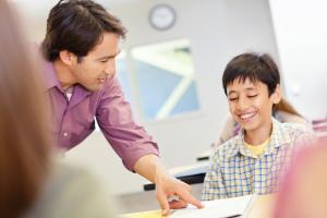 a man helping a young boy at his desk