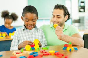 a man helpinga boy build something with shaped blocks