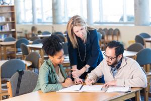 Three adults looking at paperwork together.