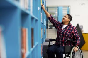 Young man in wheelchair reaching for book