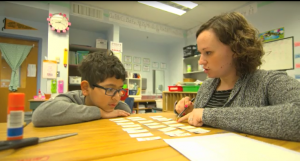woman working with boy using flash cards on a table