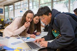 three young people looking at a laptop screen