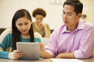 a man looking over a book with a young woman