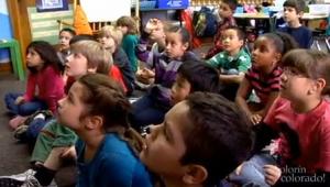 a large group of students sitting on the floor and listening