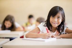 girl smiling at camera while she writes