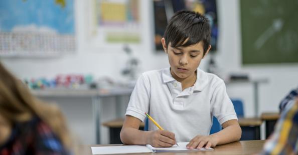 Student writing at desk