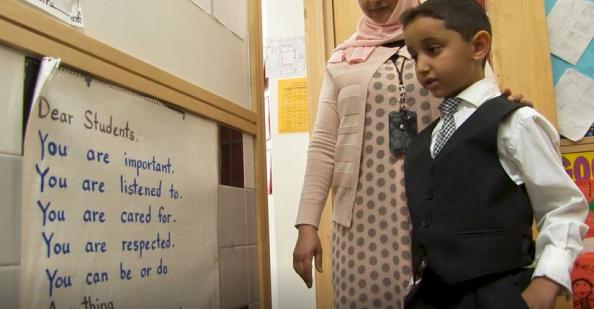 Student reading special letter on the wall to teacher