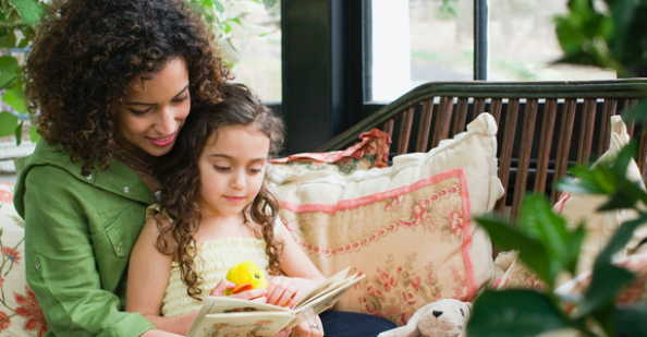 Mom and daughter reading on couch in front of window