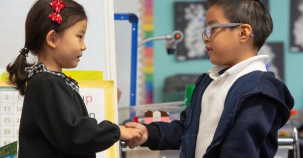 How to Create a Welcoming Classroom Environment for ELLs Girl and boy shaking hands in classroom